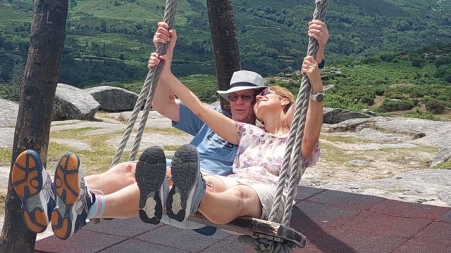 A couple joyfully swinging together in the picturesque Portuguese countryside, surrounded by lush greenery and romance