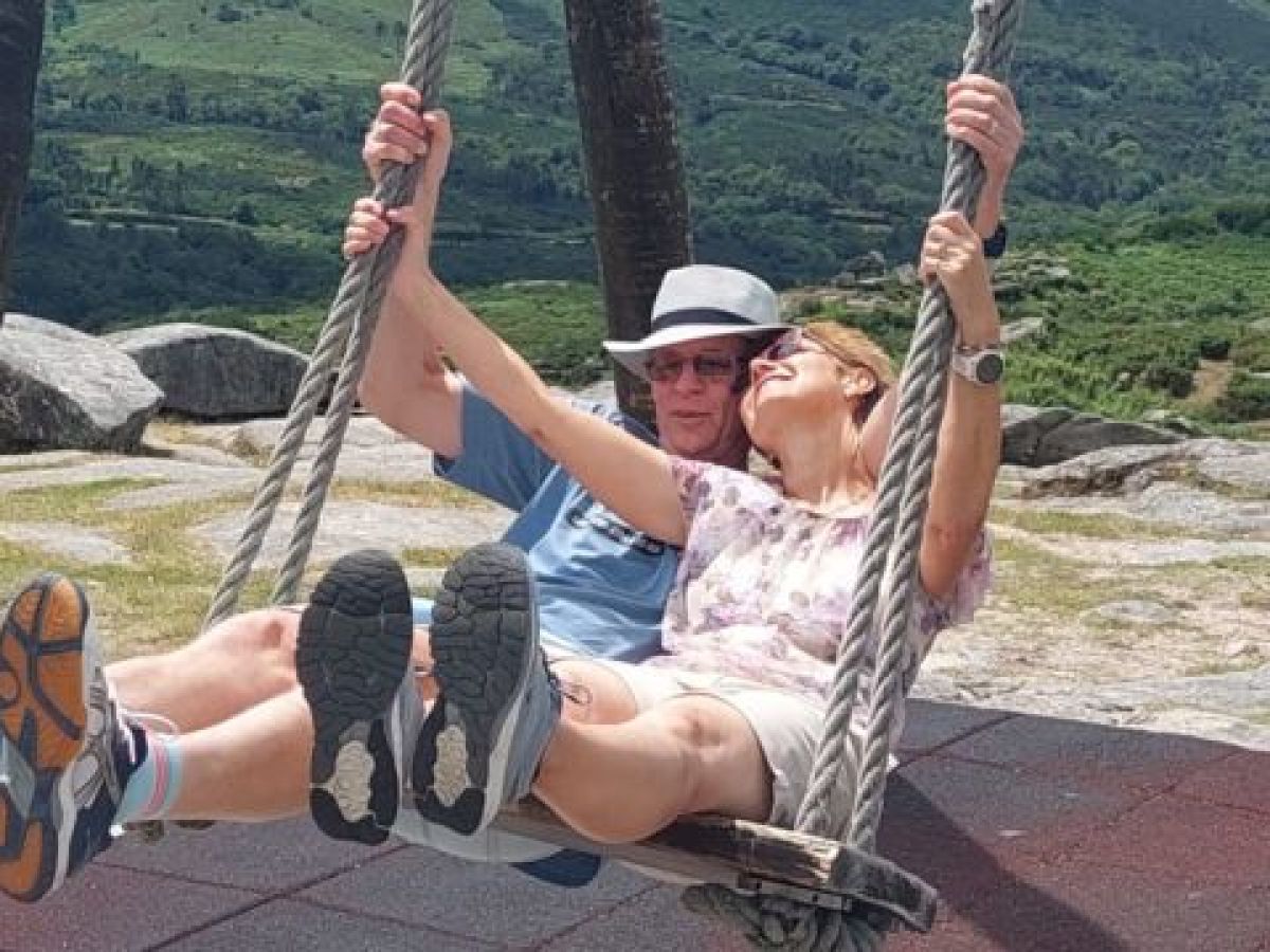 A couple joyfully swinging together in the picturesque Portuguese countryside, surrounded by lush greenery and romance