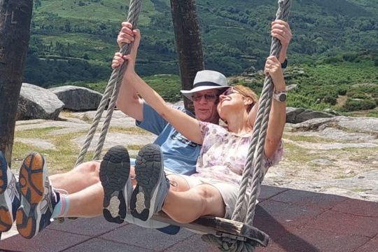 A couple joyfully swinging together in the picturesque Portuguese countryside, surrounded by lush greenery and romance