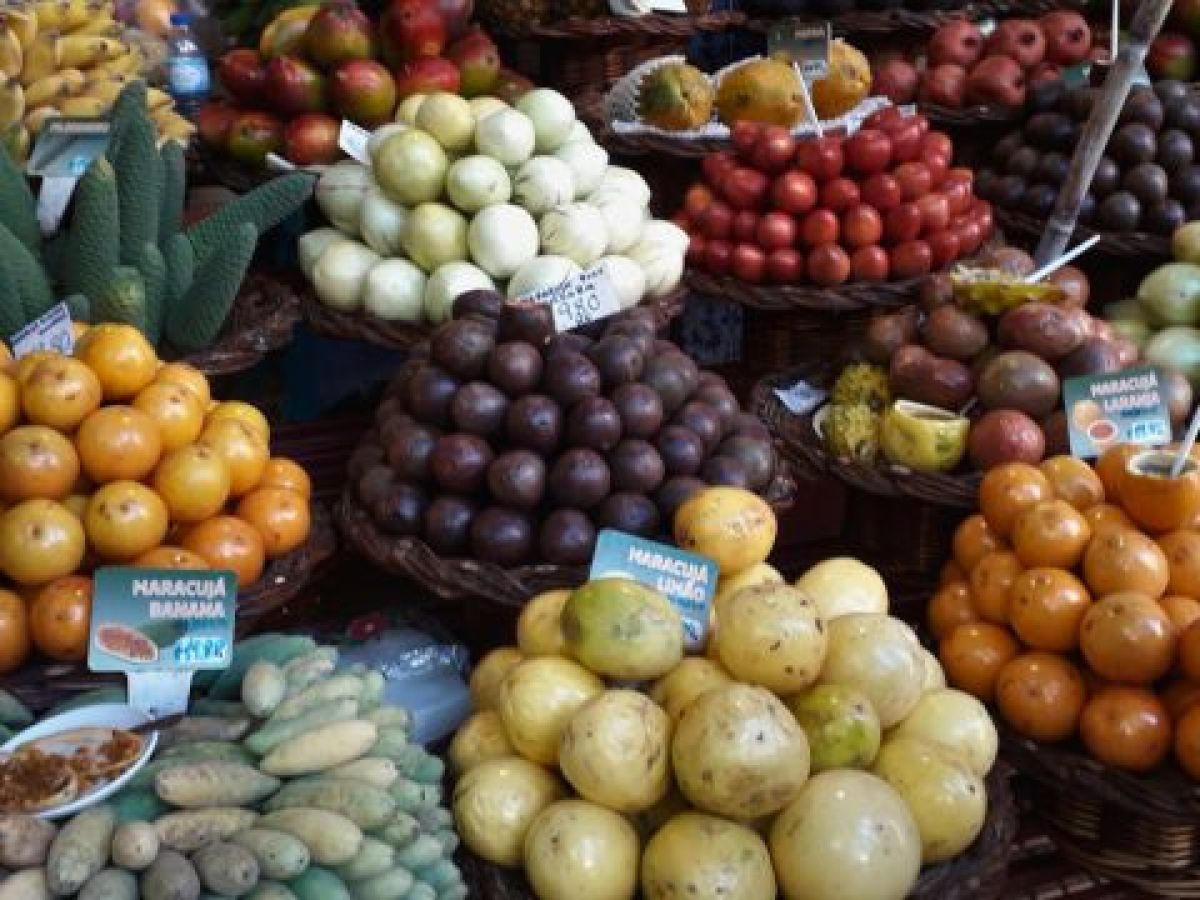 A vibrant display of assorted fruits suspended from the ceiling, showcasing the colorful markets of Funchal, Madeira.