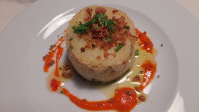 A beautifully arranged potato dish on a white plate, ideal for singles seeking culinary vacation experiences.