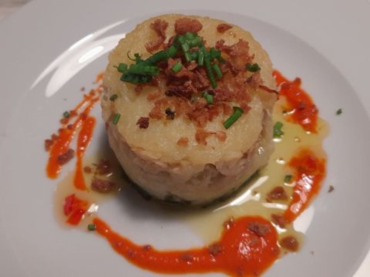 A beautifully arranged potato dish on a white plate, ideal for singles seeking culinary vacation experiences.