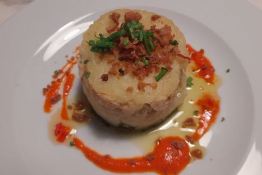 A beautifully arranged potato dish on a white plate, ideal for singles seeking culinary vacation experiences.