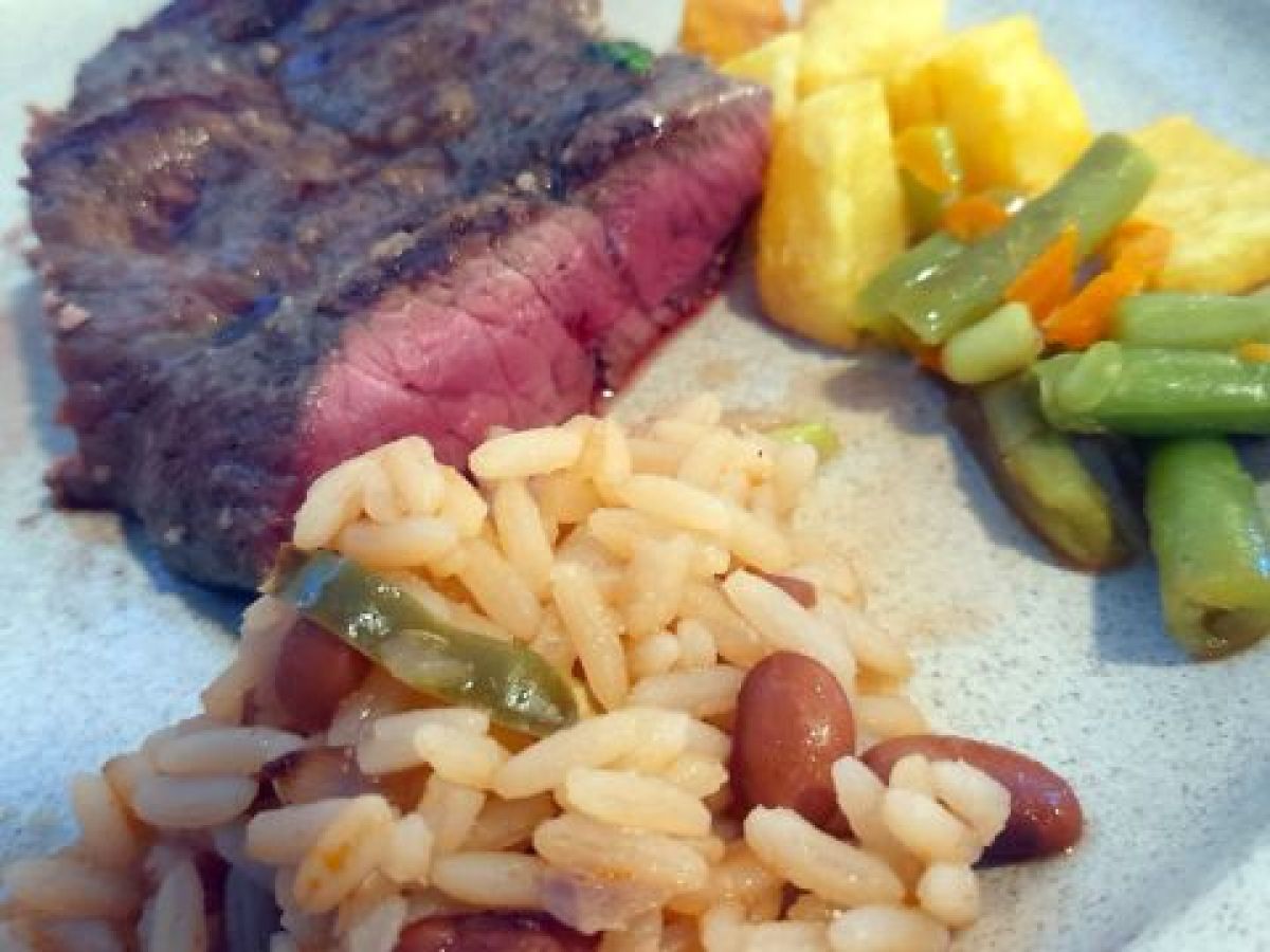 A delicious plate featuring Cachena steak, accompanied by beans and rice, perfect for a food and wine tour in Portugal.