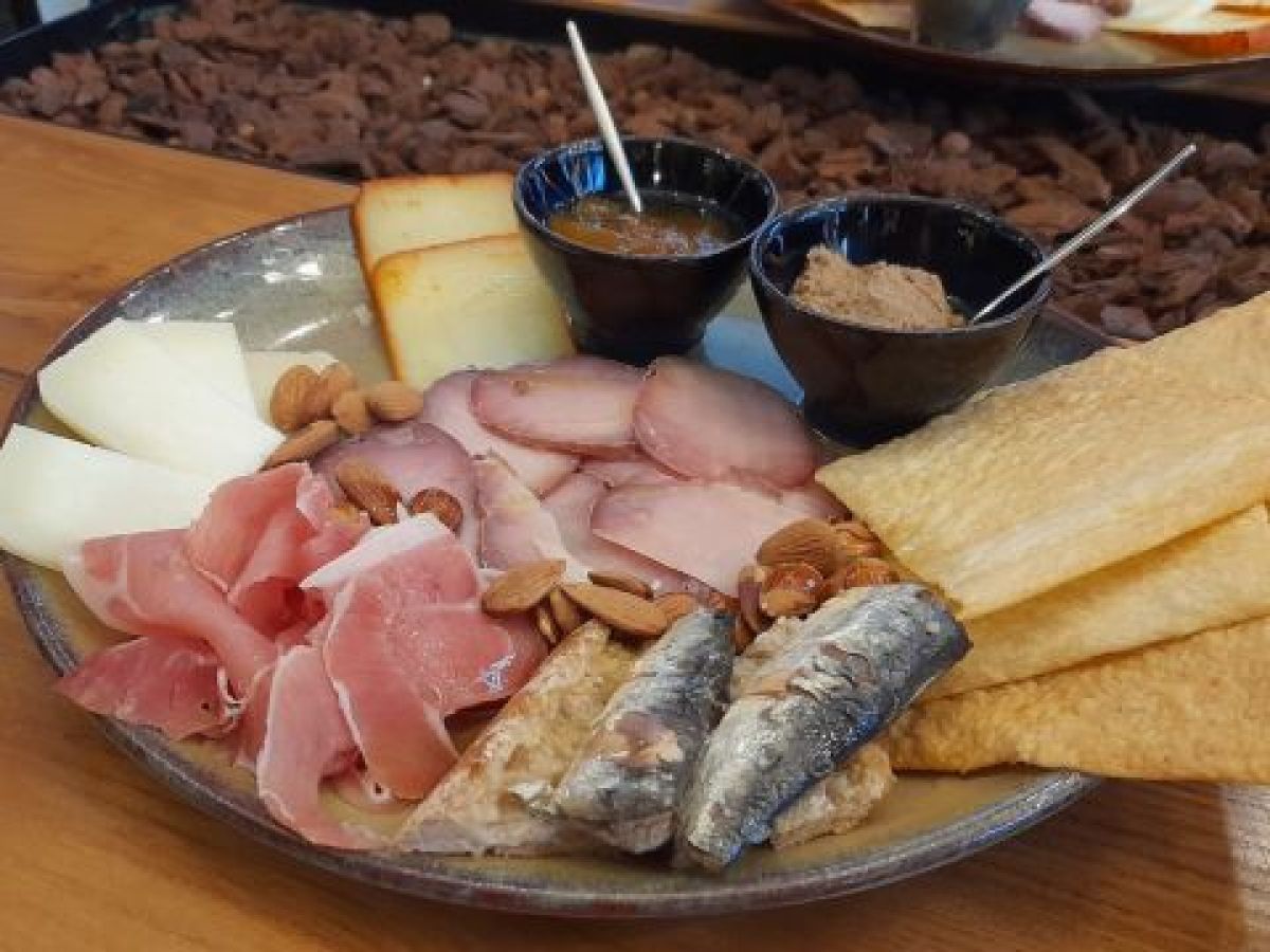 A delicious plate featuring savory meat, creamy cheese, and crunchy crackers, perfect for a food and wine tour in Portugal.