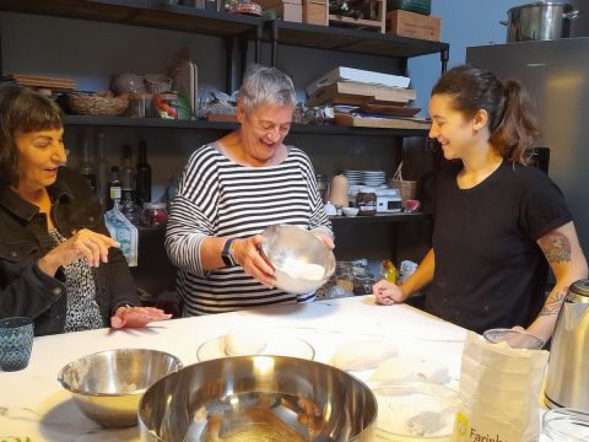 A diverse group of individuals collaborates in a bright kitchen, creating authentic Portuguese cuisine during a cooking retreat.