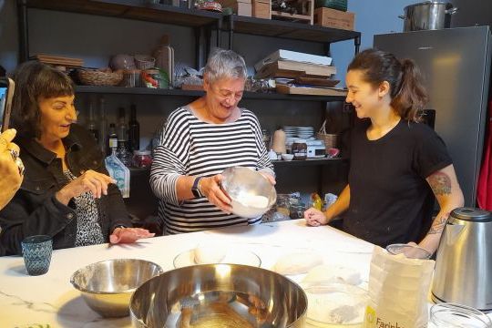 A diverse group of individuals collaborates in a bright kitchen, creating authentic Portuguese cuisine during a cooking retreat.