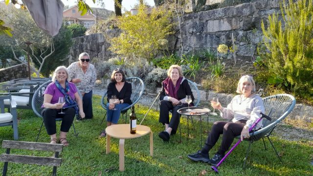 A group of women enjoying a Lisbon food and wine tour, seated on chairs in the grass, surrounded by vibrant greenery.