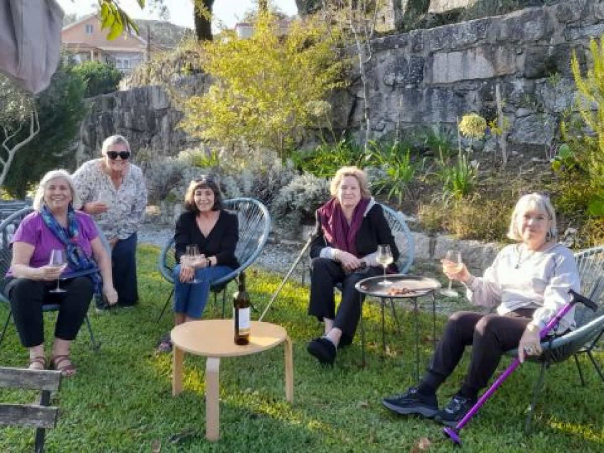 A group of women enjoying a Lisbon food and wine tour, seated on chairs in the grass, surrounded by vibrant greenery.