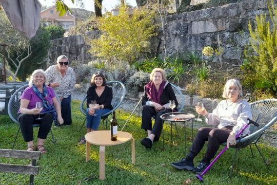 A group of women enjoying a Lisbon food and wine tour, seated on chairs in the grass, surrounded by vibrant greenery.