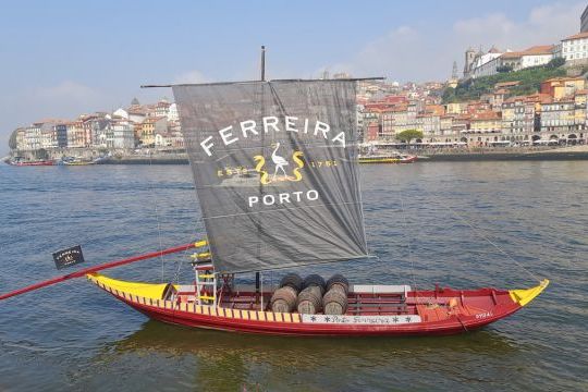 A sailboat glide on the Douro River, with the vibrant city of Porto in the background, showcasing a scenic tour experience.