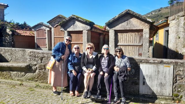 A small group of five women poses in front of a picturesque building, enjoying a break on their Portuguese food and wine tour.