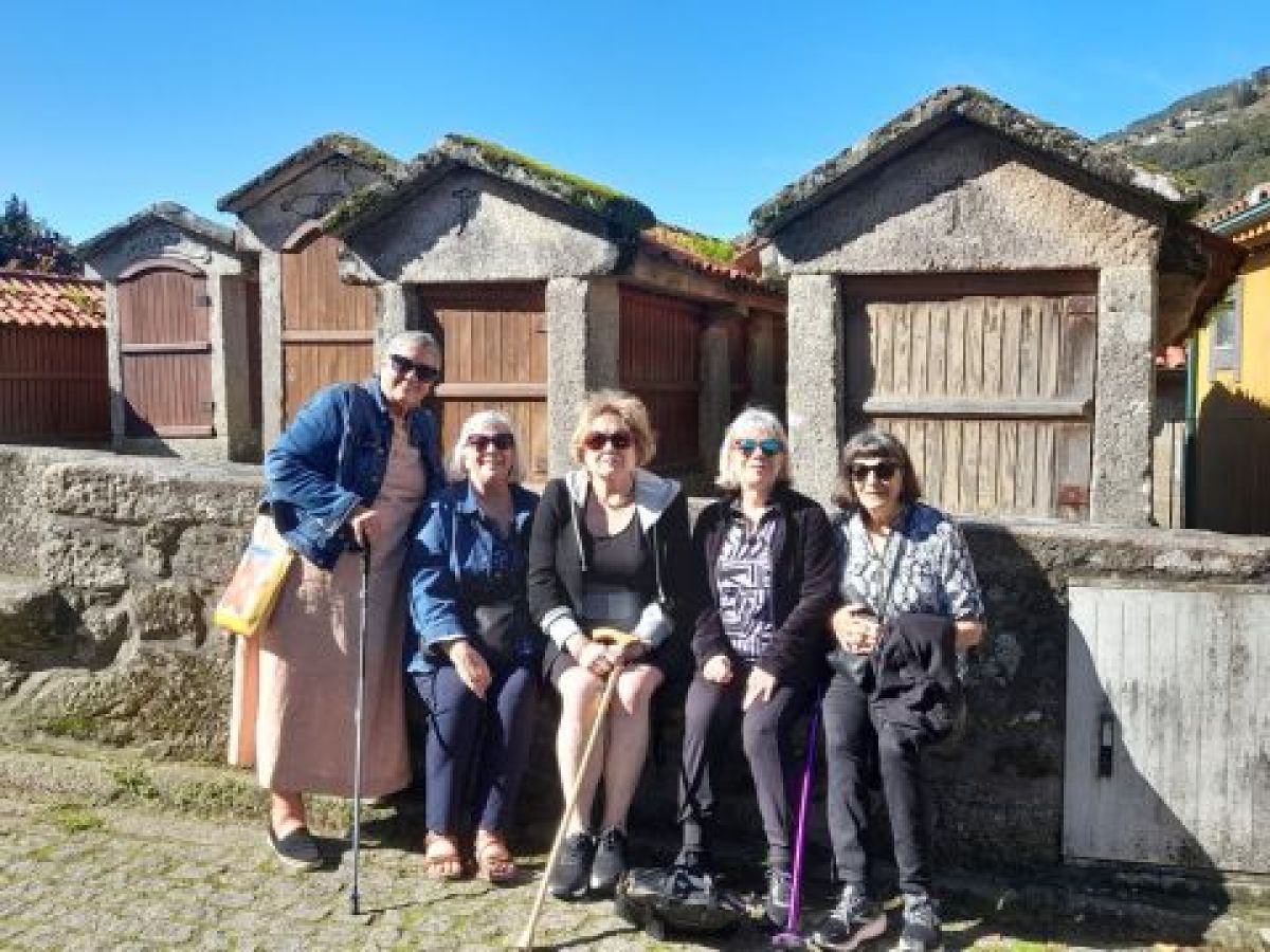 A small group of five women poses in front of a picturesque building, enjoying a break on their Portuguese food and wine tour.