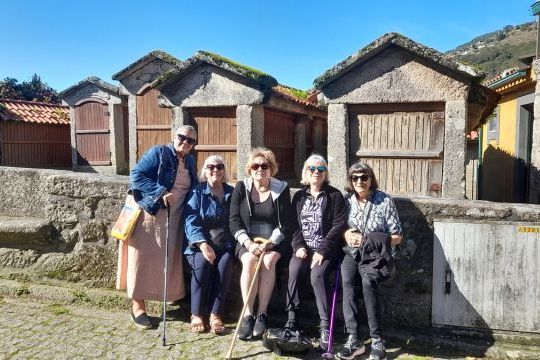 A small group of five women poses in front of a picturesque building, enjoying a break on their Portuguese food and wine tour.