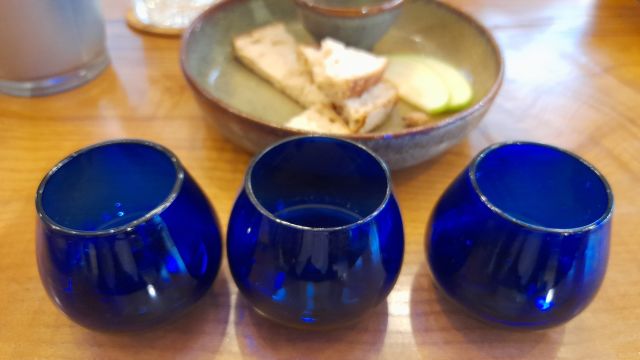 Three blue glass cups arranged on a wooden table, ready for a delightful Porto olive oil tasting session.