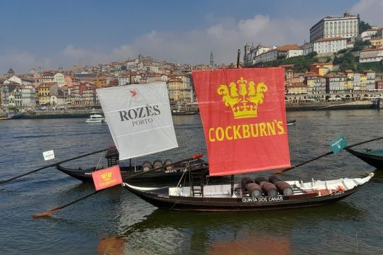 Two boats with sails drift on the Douro River, with Porto's beautiful skyline in view, ideal for exploring Portugal's charm.