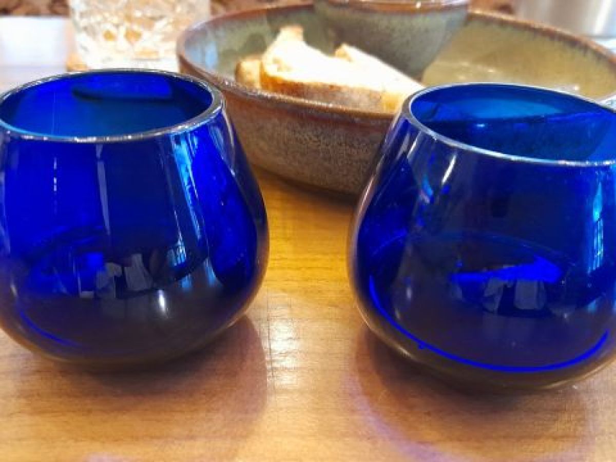 blue glass cups arranged on a wooden table, ready for a delightful Porto olive oil tasting session.
