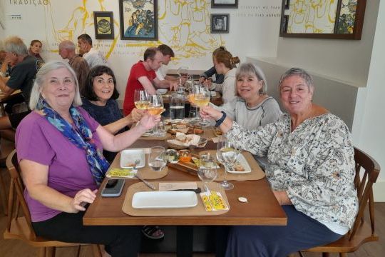 A lively group enjoying wine at a table during a small-group Portuguese food tour in Lisbon.