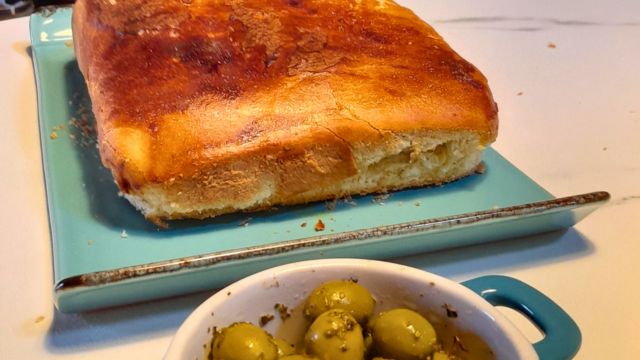 A beautiful loaf of bread on a blue plate with olives, created in our delightful cooking class in Portugal