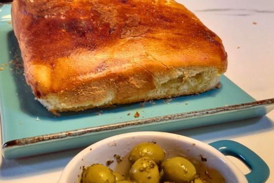A beautiful loaf of bread on a blue plate with olives, created in our delightful cooking class in Portugal