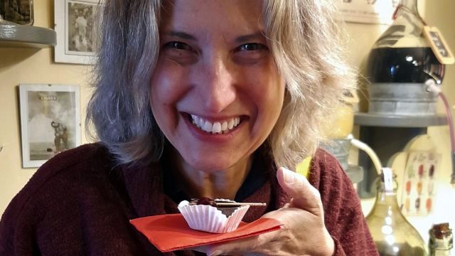 In Obidos, Portugal, a woman savors a cupcake with chocolate, paired with a glass of ginja