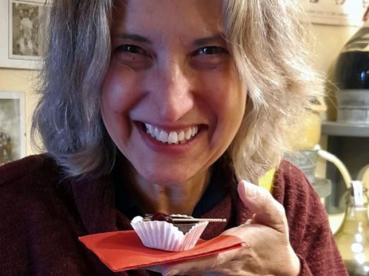 In Obidos, Portugal, a woman savors a cupcake with chocolate, paired with a glass of ginja