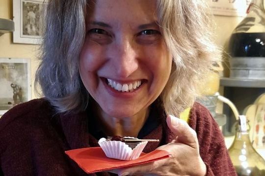 In Obidos, Portugal, a woman savors a cupcake with chocolate, paired with a glass of ginja