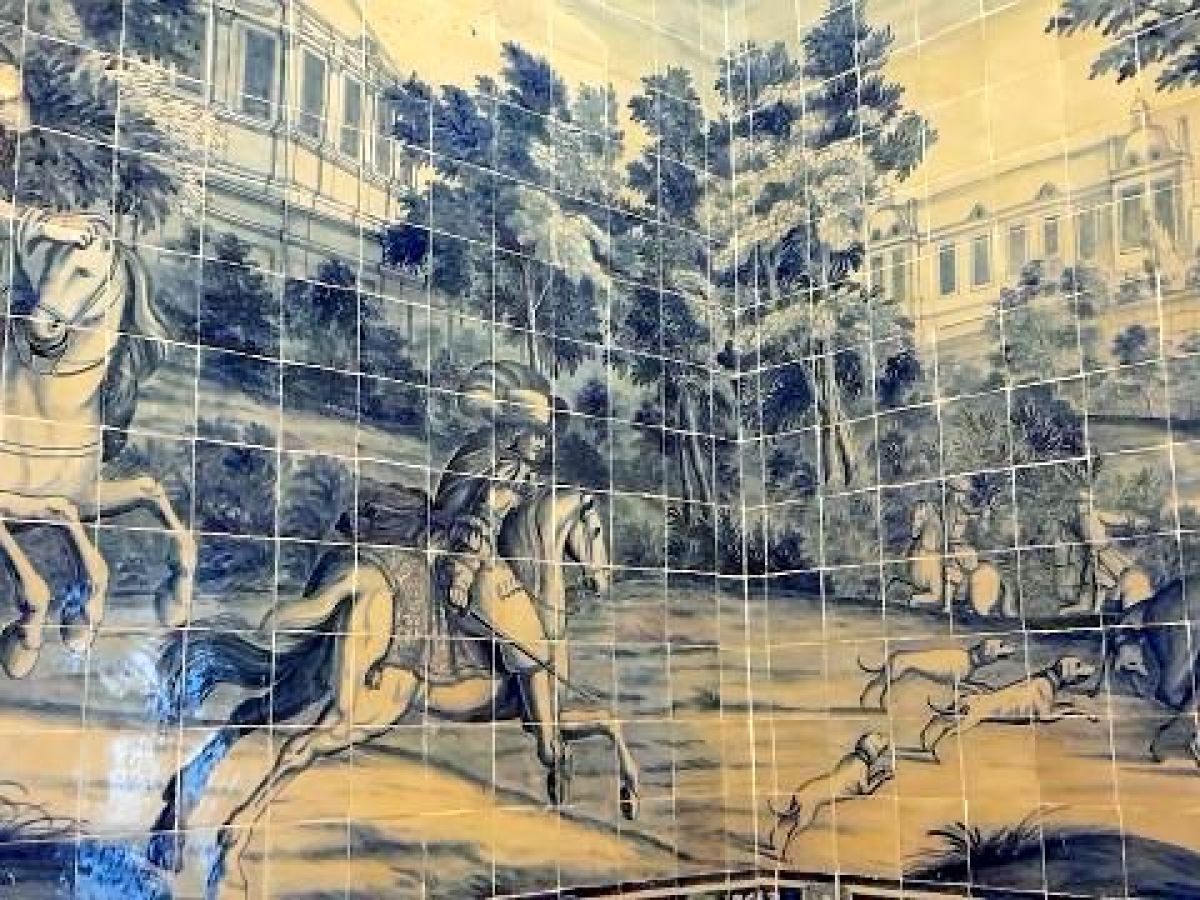 A mural depicting horses and people in a palace, complemented by Portuguese tiles appreciated by a small tour group.