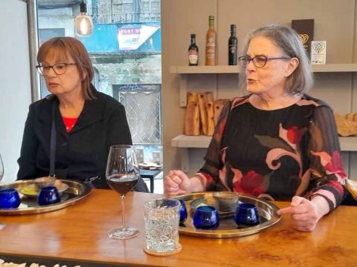 Two women at a table in Porto, Portugal, sipping wine and participating in an olive oil tasting.