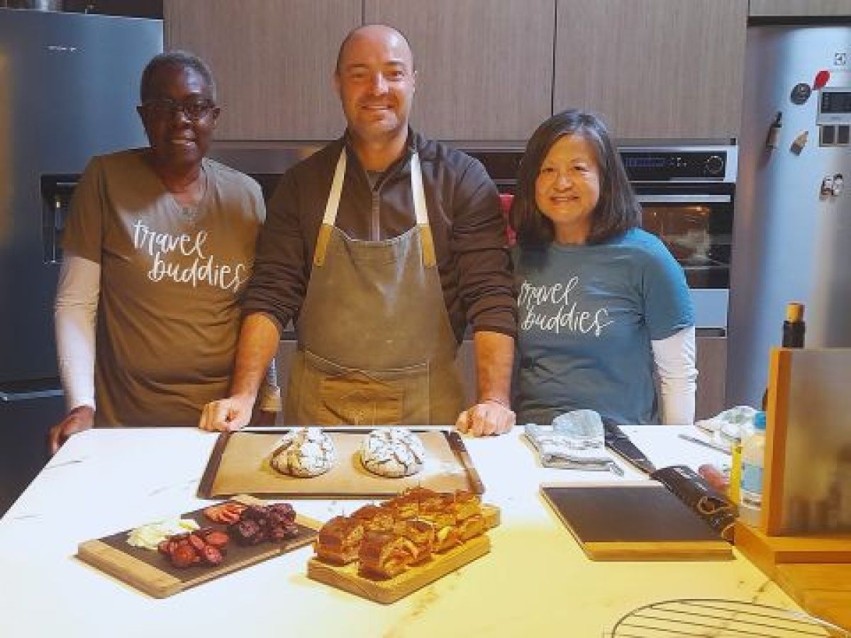 A small group of three stands at a kitchen counter, surrounded by food, after completing a cooking class in Portugal.
