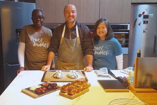 A small group of three stands at a kitchen counter, surrounded by food, after completing a cooking class in Portugal.