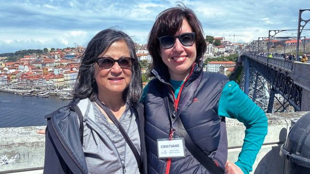Guide Cris Fonte and a guest pose on a bridge in Porto, with the vibrant cityscape behind them during a walking tour.