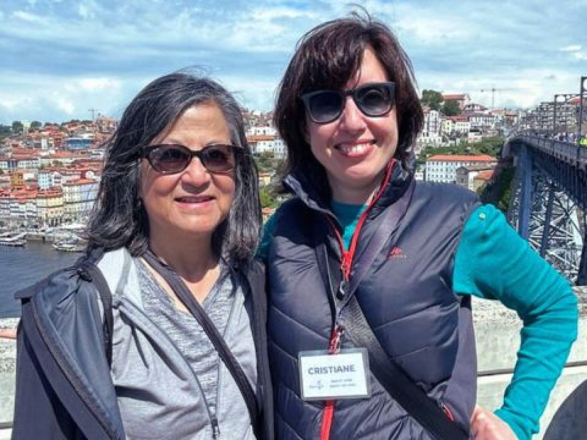 Guide Cris Fonte and a guest pose on a bridge in Porto, with the vibrant cityscape behind them during a walking tour.