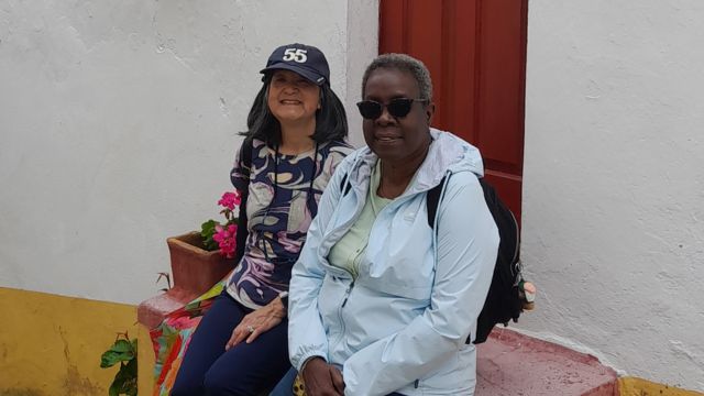 Two women sit on steps outside a house in Obidos, enjoying a small group tour in the charming medieval village of Portugal.