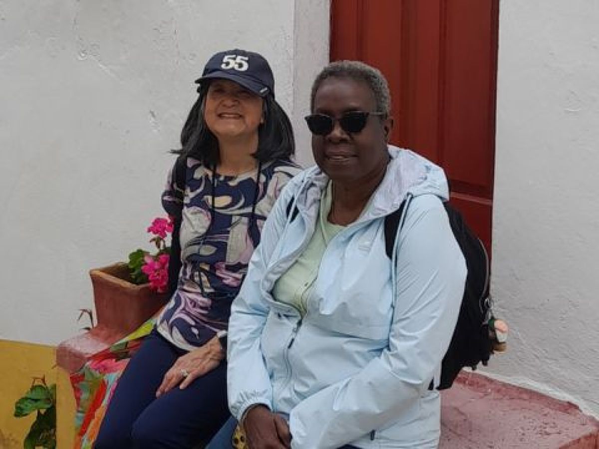Two women sit on steps outside a house in Obidos, enjoying a small group tour in the charming medieval village of Portugal.