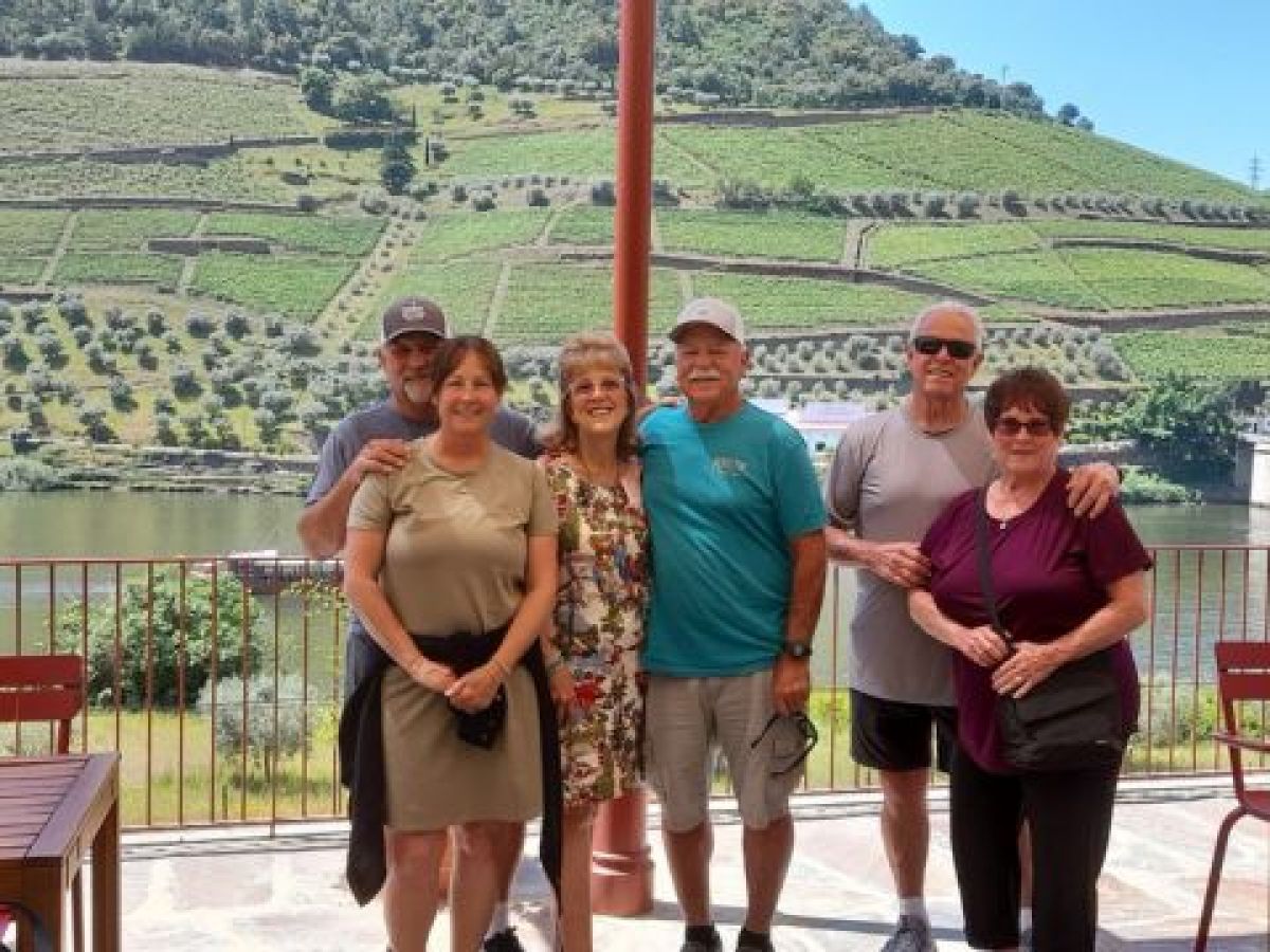 A small private tour group poses by the Douro River in Portugal, smiling after a full day of exploration in the valley.