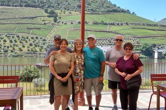 A small private tour group poses by the Douro River in Portugal, smiling after a full day of exploration in the valley.