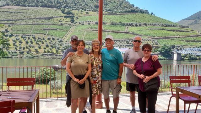 A small private tour group poses by the Douro River in Portugal, smiling after a full day of exploration in the valley.