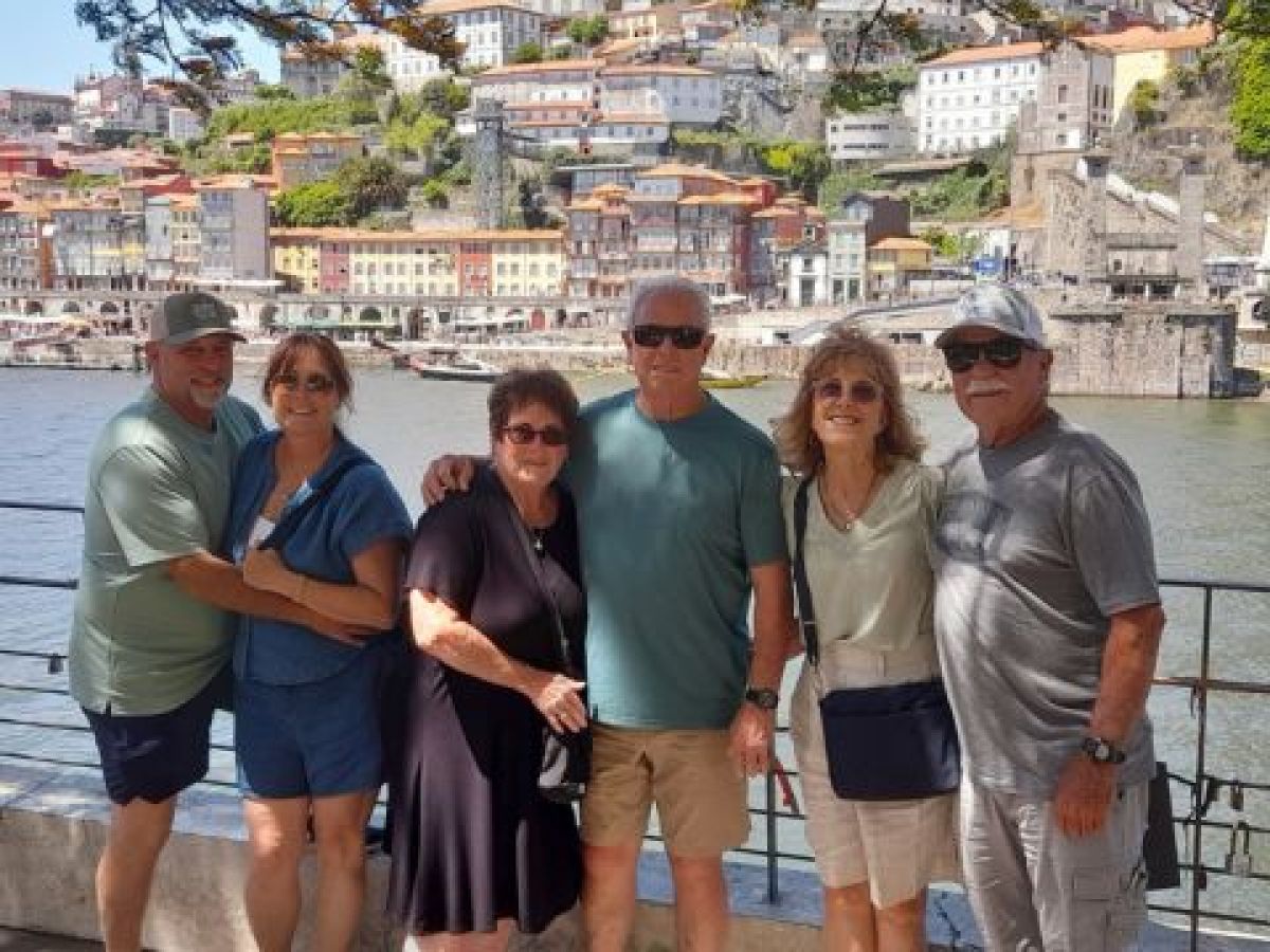 A small private tour group poses for a photo by a river during their full day exploring Porto, Portugal.