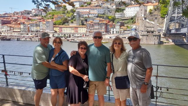 A small private tour group poses for a photo by a river during their full day exploring Porto, Portugal.