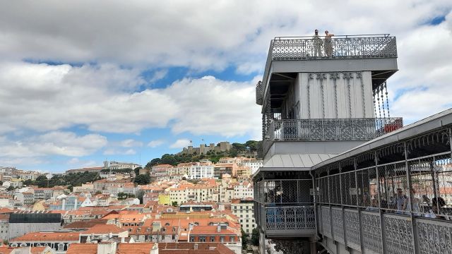 A panoramic view of Lisbon from the top of Elevador Santa Justa, showcasing the city's rooftops and historic architecture.