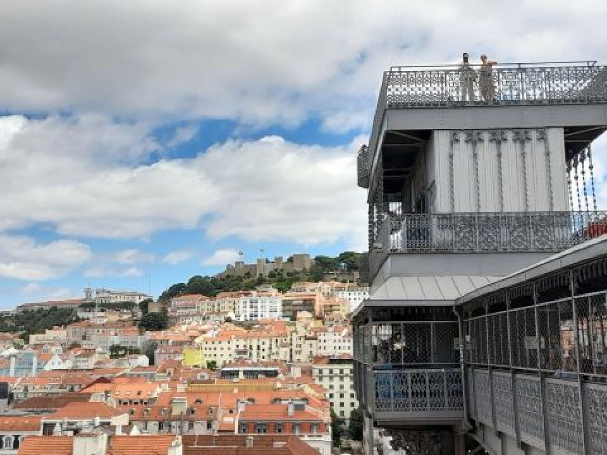 A panoramic view of Lisbon from the top of Elevador Santa Justa, showcasing the city's rooftops and historic architecture.