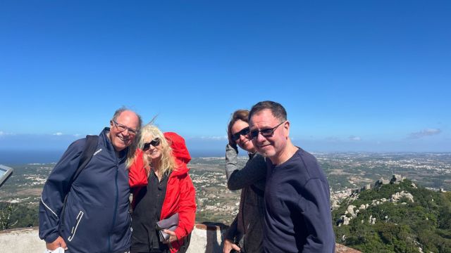 A group of four stands smiling in front of Pena Palace, captured during a private tour in Sintra, highlighting the Moors castle.