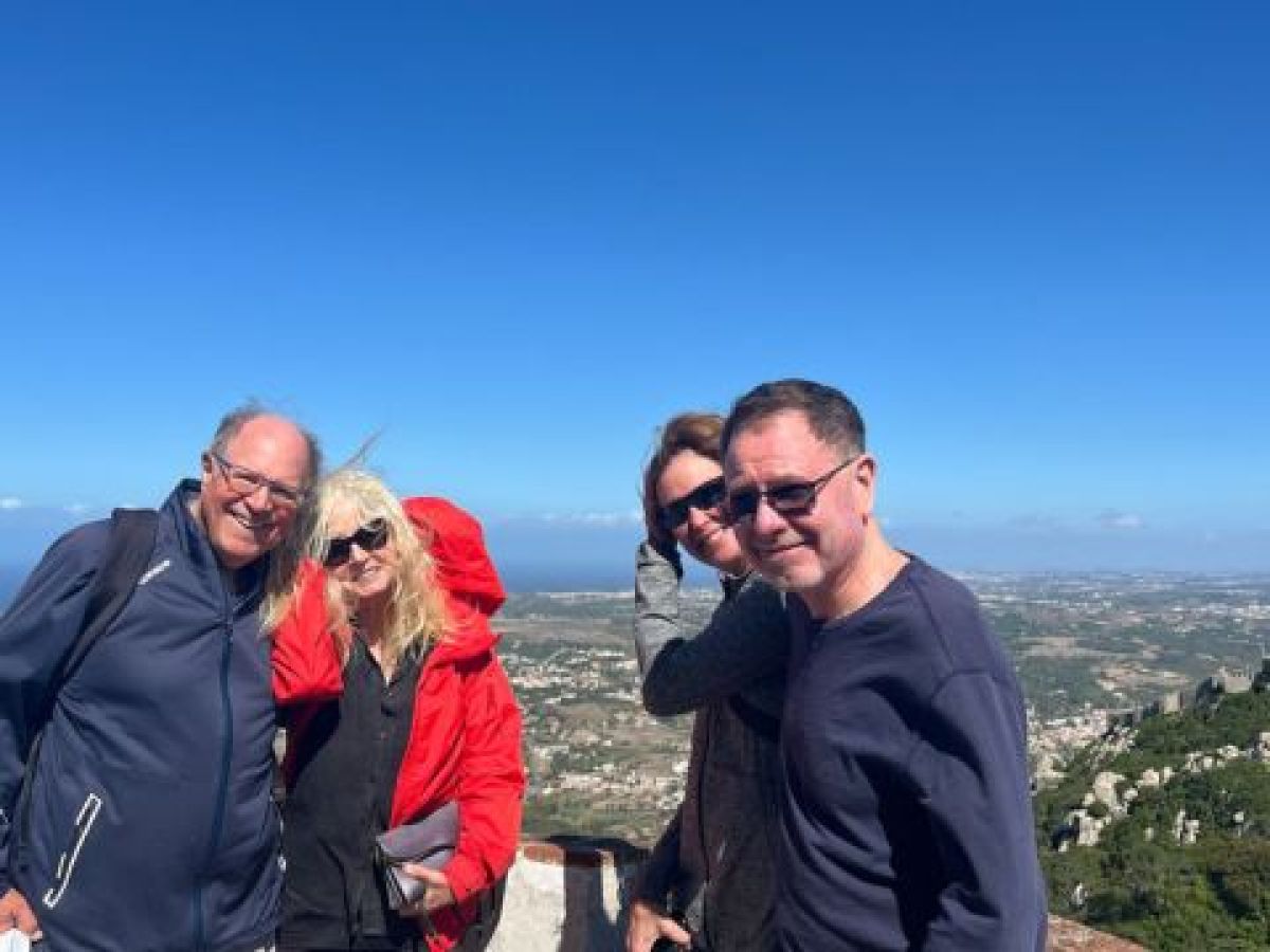 A group of four stands smiling in front of Pena Palace, captured during a private tour in Sintra, highlighting the Moors castle.