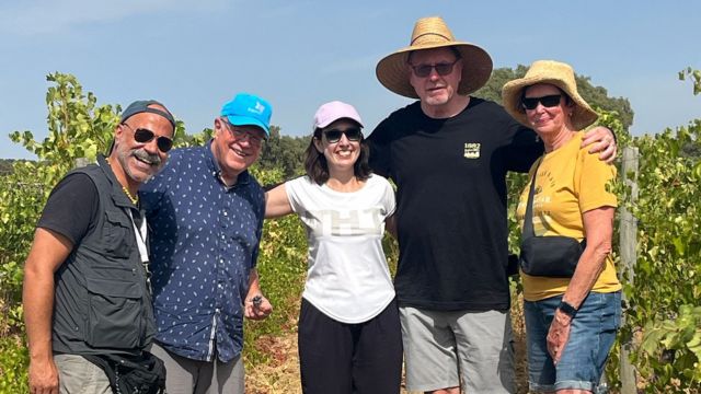 A group of people smiling for a photo during a private cork tour in a vineyard in Évora, Portugal, enjoying wine production.summer clothing.