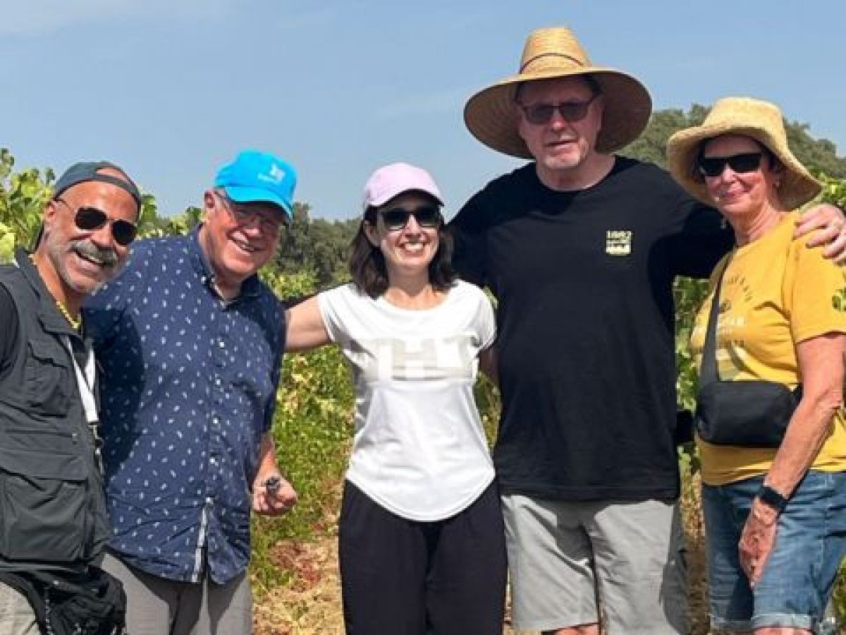 A group of people smiling for a photo during a private cork tour in a vineyard in Évora, Portugal, enjoying wine production.summer clothing.