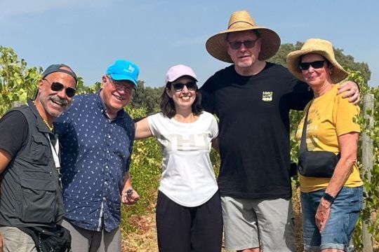 A group of people smiling for a photo during a private cork tour in a vineyard in Évora, Portugal, enjoying wine production.summer clothing.