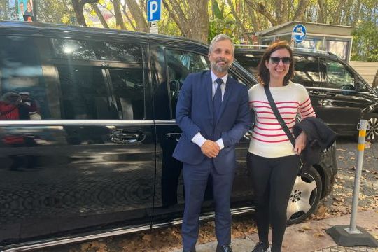 A man and woman stand beside a black luxury van, ready for their private tour.