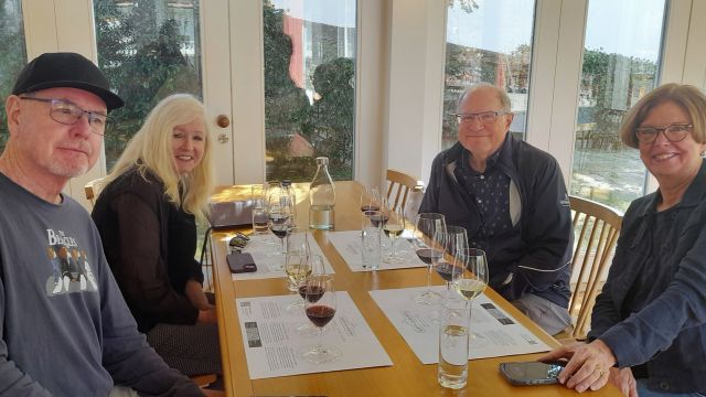 Four people enjoying a private wine tour in the Douro Valley, seated at a table with wine glasses in hand.