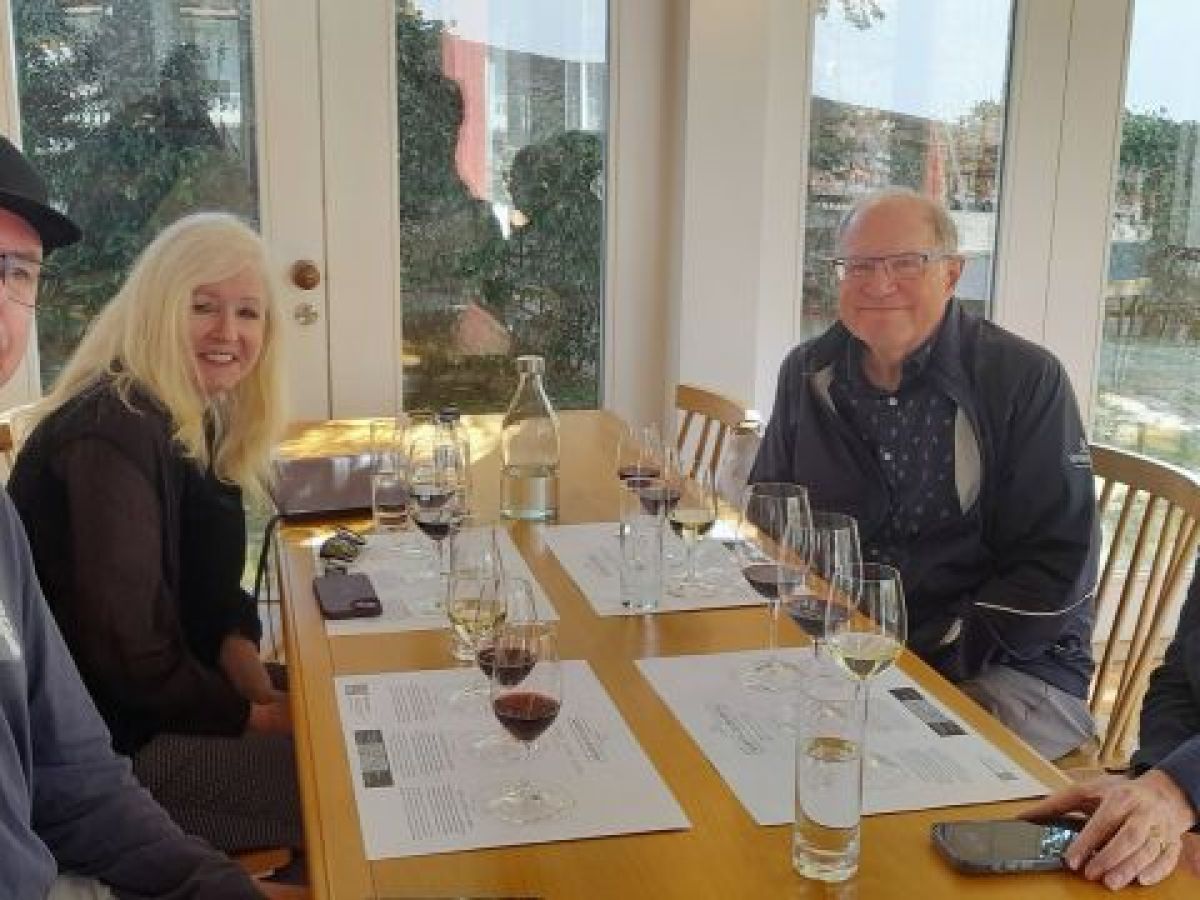 Four people enjoying a private wine tour in the Douro Valley, seated at a table with wine glasses in hand.